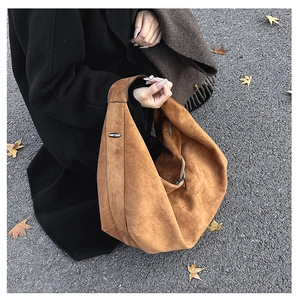 Brown suede hobo shoulder bag with zipper and metal hardware shown in outdoor setting