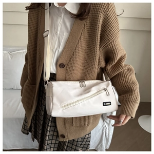 Détail d'un sac bandoulière blanc minimaliste avec poche zippée et bandoulière réglable