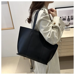 Detail view of smooth black faux leather texture and reinforced stitching on tote bag