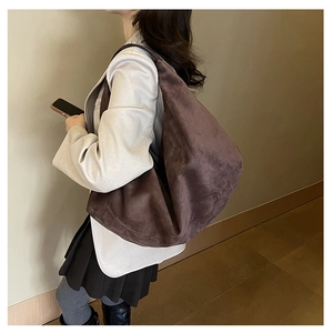 Detailed view of a large dark brown suede tote bag worn as a shoulder bag on a model