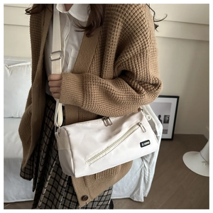 Détail du sac bandoulière blanc cassé avec poche zippée et étiquette Fashion brodée
