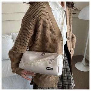 Détail d'un sac bandoulière beige crème montrant sa texture douce et son étiquette tissée