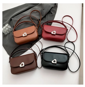 Detail of four chic faux leather saddle bags with heart-shaped metal buckles in rich colors