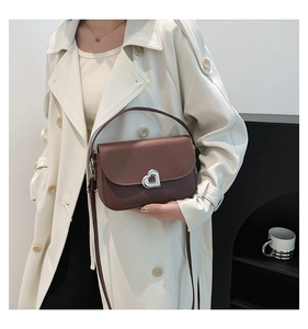 Brown leather saddle bag featuring a stylish silver heart-shaped metal buckle detail
