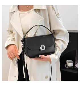 Detail view of a black leather handbag featuring a silver heart-shaped metal twist lock