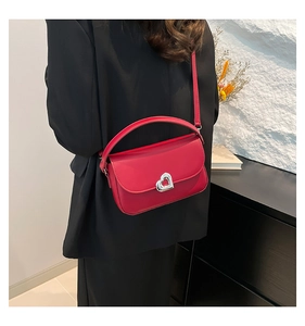 Detail of red leather bag featuring heart-shaped metal clasp and flap cover