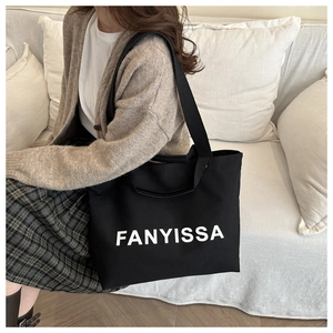 Close-up of black canvas tote bag with white FANYISSA lettering and shoulder straps