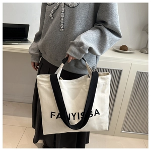 Detail of white canvas lunch bag with black FANYISSA logo and wide shoulder straps