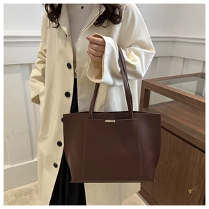 Detail of deep brown leather tote bag showing high-capacity design and sleek shoulder straps