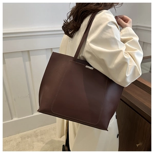 Close-up of a large coffee brown tote bag showing long straps and metal top details