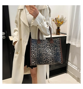 Detail of trendy leopard print tote bag with brown handles carried by model in trench coat