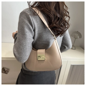 Beige crescent shoulder bag styled with a neutral outfit in a minimalist room