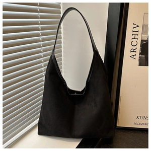 Detail of minimalist black faux suede tote bag displayed by a window with natural lighting