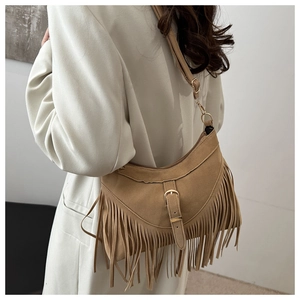 Close-up of brown suede moon bag featuring long fringe tassels and a golden buckle