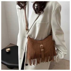 Close-up of brown suede crossbody bag with long fringes and gold metal buckle detail
