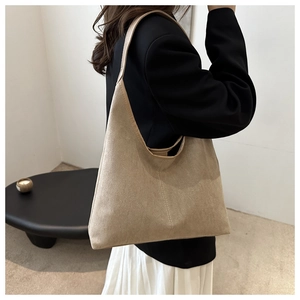 Grand sac cabas en daim kaki porté avec un blazer noir pour un look de bureau
