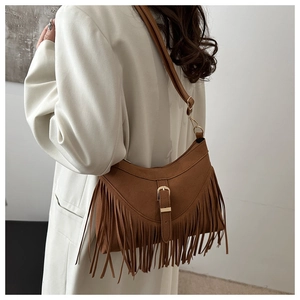 Detalle del bolso bohemio de ante marrón con flecos y hebilla decorativa en modelo