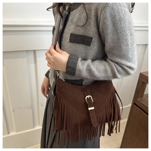 Detail of vintage brown suede crossbody bag with decorative tassels and gold hardware