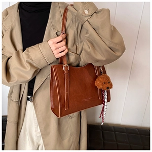 Dettaglio borsa shopper vintage marrone in similpelle con ciondolo a forma di cane