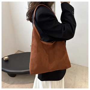 Sac fourre-tout en daim marron porté à l'épaule, grande capacité et design minimaliste