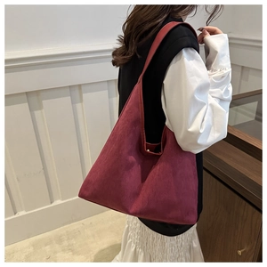 Détail du grand sac hobo bordeaux en daim porté par un mannequin dans un décor épuré