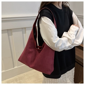 Détail de la texture en daim bordeaux mat d'un grand sac cabas à bandoulière pour femme