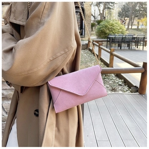 Close-up of pink frosted leather envelope bag with gold chain strap on model