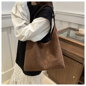 Dettaglio di borsa tote in pelle scamosciata marrone scuro con tracolla in pelle
