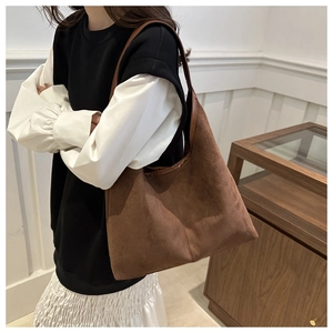 Close-up of a large dark brown suede tote bag showing its matte texture and shoulder strap