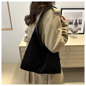 Détail d'un grand cabas en daim noir au design minimaliste et aux anses en cuir souple