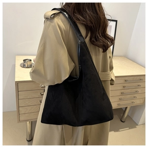 Detail of minimalist black suede tote bag showing large capacity and smooth leather strap