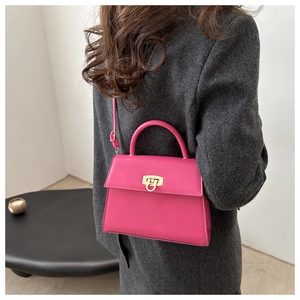 Detail einer rosaroten Lederhandtasche mit goldenem Drehverschluss und rundem Griff