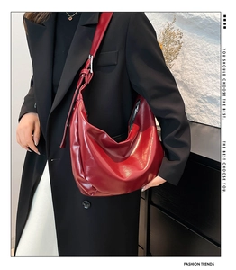 Detail of red glossy patent leather crescent bag with adjustable silver buckle strap