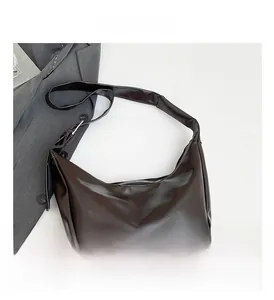 Close-up of glossy dark brown hobo bag with adjustable strap on professional suit