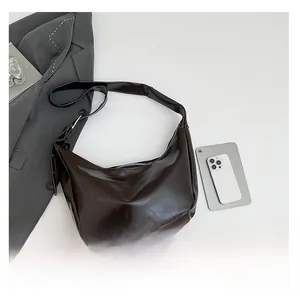 Detail of a dark brown crescent bag with wide shoulder strap and soft leather texture
