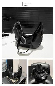 Detail of black glossy Hobo bag with silver grommet shoulder strap and metal zipper