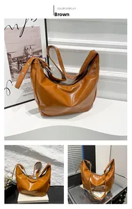Detail view of large brown faux leather hobo bag with silver metal eyelets on the strap