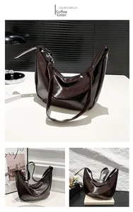 Detail view of brown glossy half-moon shoulder bag with adjustable strap and silver hardware