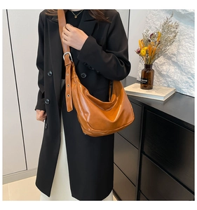 Detail of caramel crescent shoulder bag showing wide strap and polished PU leather texture
