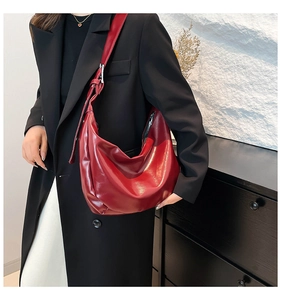 Detail of red oversized leather hobo bag with adjustable strap worn on black blazer