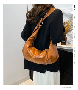 Detail of a brown pleated shoulder bag with a unique knotted strap and glossy finish
