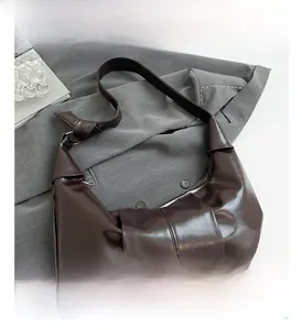 Detail view of coffee brown PU leather hobo bag with knotted strap and pleated texture