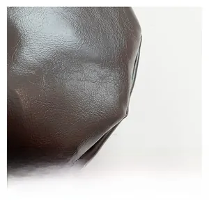 Detail of dark brown faux leather texture with soft pleats and subtle glossy finish