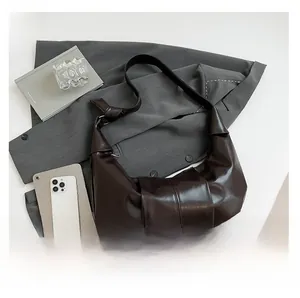 Detail of dark brown pleated leather shoulder bag with knotted strap and glossy finish