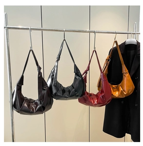 Detailed view of four pleated croissant bags in different colors hanging on a rack