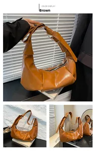 Detail showing the brown PU leather knot handle design and smooth zipper on the crescent bag