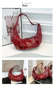 Detailed view of red hobo bag with pleated texture and knot strap on marble surface