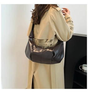 Side view of dark brown crescent bag with pleated seams and glossy leather texture