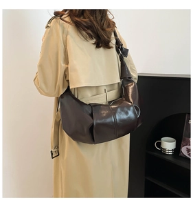 Detail view of glossy dark brown crescent bag with a unique knotted shoulder strap style