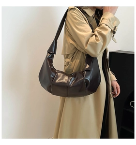 Detail of chocolate glossy leather hobo bag with pleated texture and stylish knotted strap